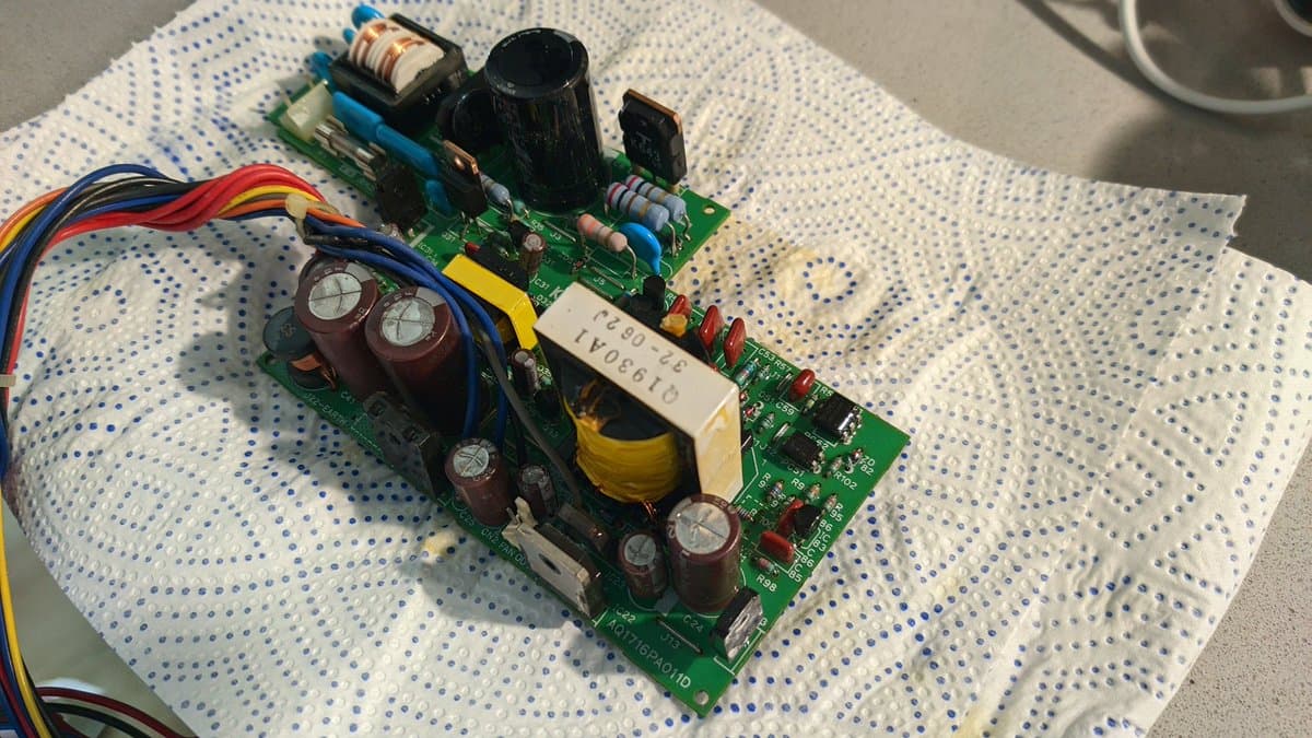 Power supply board with replaced electrolytic capacitors, transformer, and inductor on breadboard after magic smoke incident from reversed filter installation.