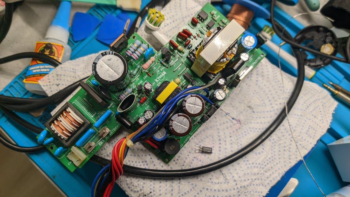 Sharp X68000 Pro II motherboard with replaced transistor Q51, showing multiple electrolytic capacitors, inductor coils, and component-level repairs on workbench.