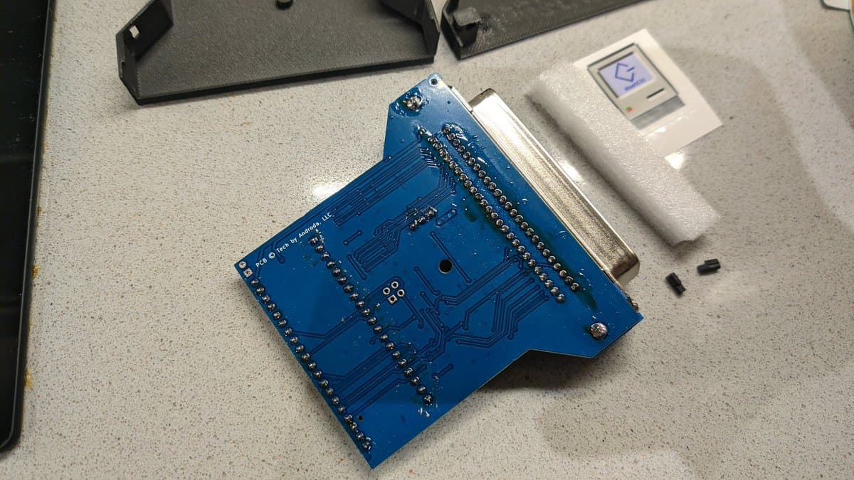 BlueSCSI v2 PCB assembly with gold-plated pins, DB25 connector, and adjacent keyboard connector shell during X68000 restoration project.