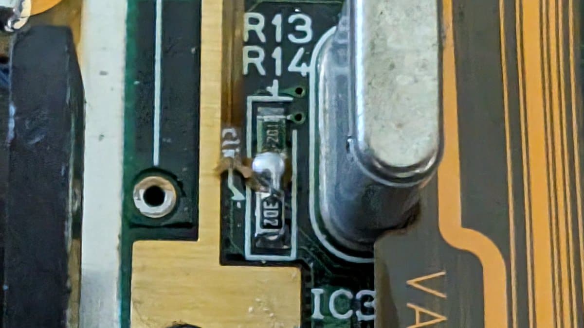 Close-up of Game Gear circuit board showing R13, R14 resistors, IC3 chip, and a clock line bodge wire repair after flex cable damage.