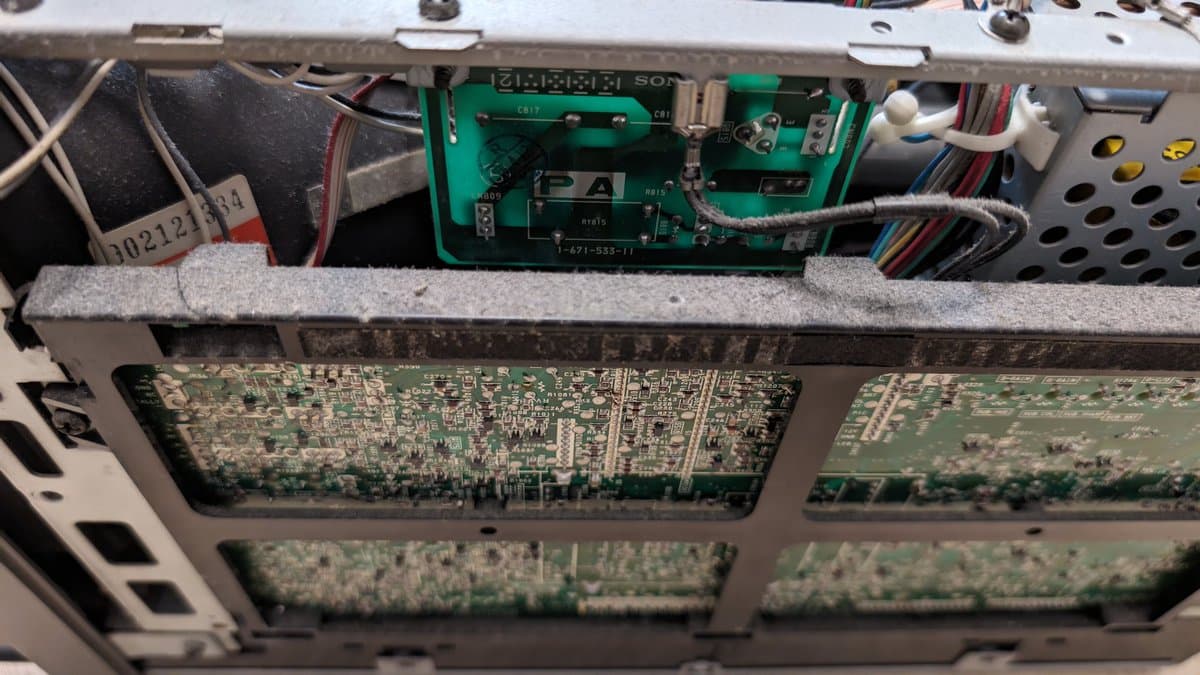 Interior of Sony PVM-9045QD showing dusty circuit boards, corroded solder joints, and accumulated debris during restoration work.
