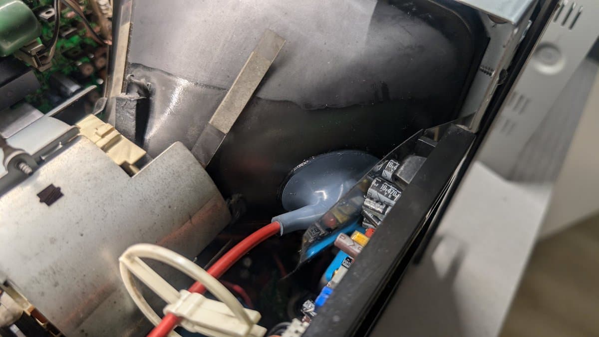 Interior view of PVM-9045QD PSU showing replacement capacitors, dielectric grease application on anode cap, and soldering work on deflection board.