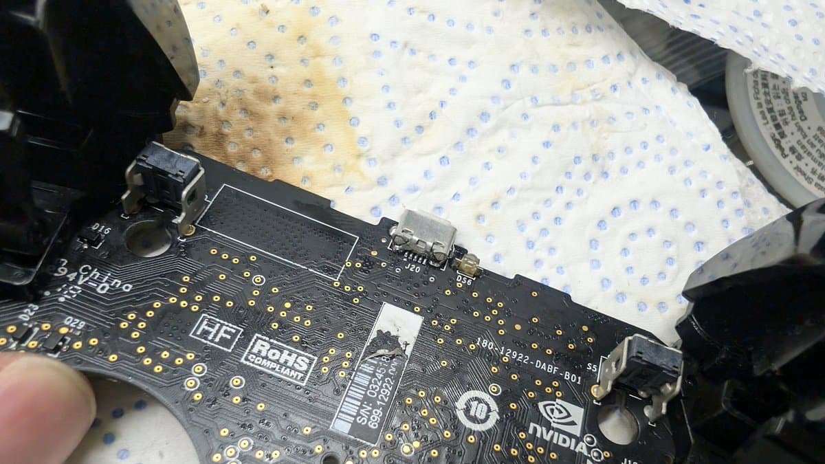 Close-up of Nvidia Shield controller PCB showing replaced USB port with gold solder pads visible, blue dotted cloth background.