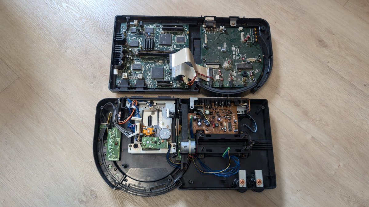 Sega Wondermega HWM-5010 disassembled showing corroded motherboard, CD drive mechanism, and power supply board with visible damage and missing components.