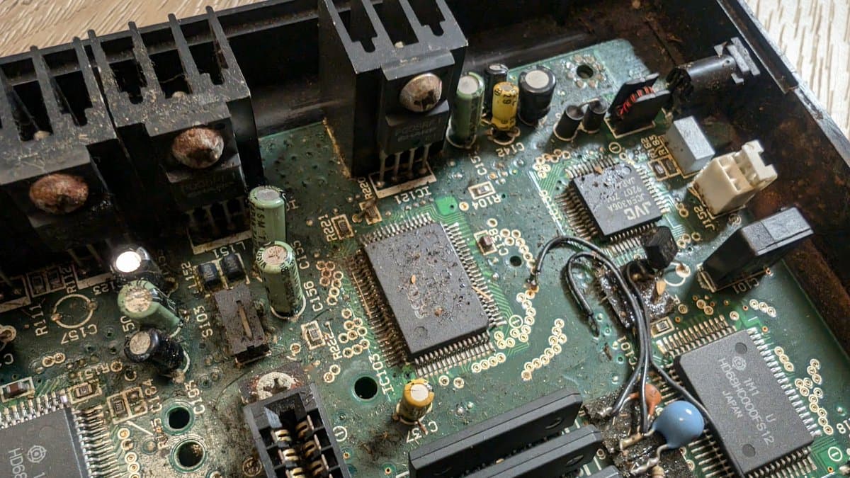 Cleaned Sega Wondermega mainboard showing corrosion removal, exposed IC chips, capacitors, and heat-sinked transistors after isopropyl treatment.