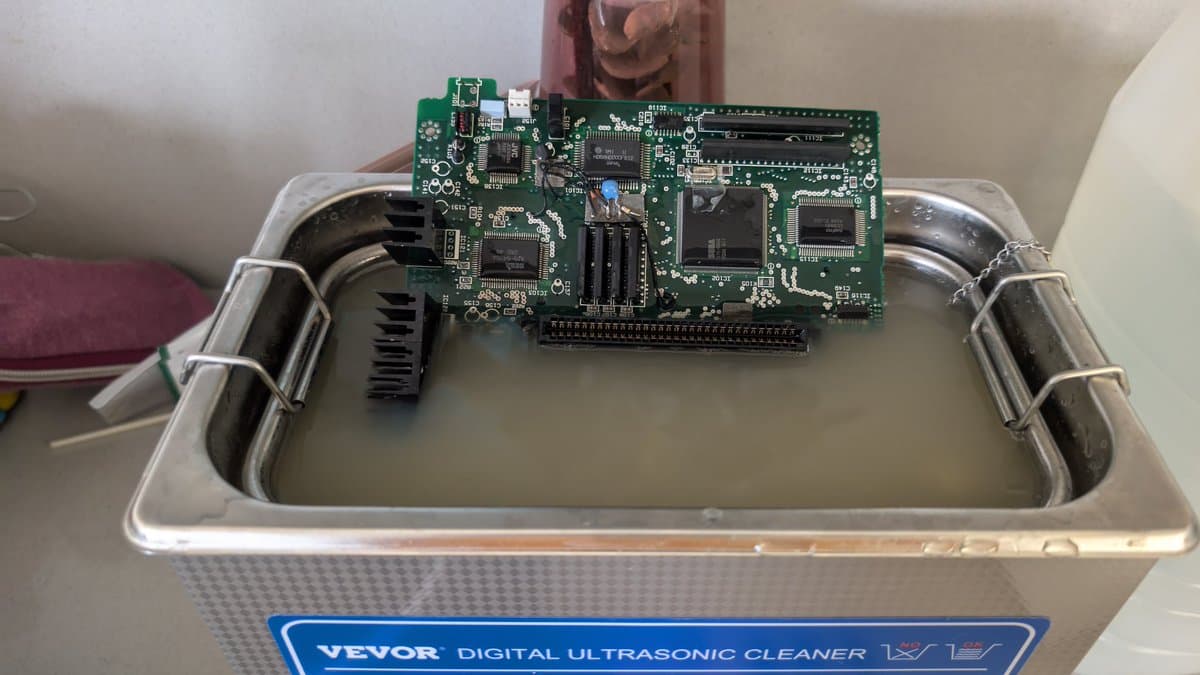 Sega Wondermega main board in VEVOR ultrasonic cleaner tank, mid-cleaning process to remove corrosion.