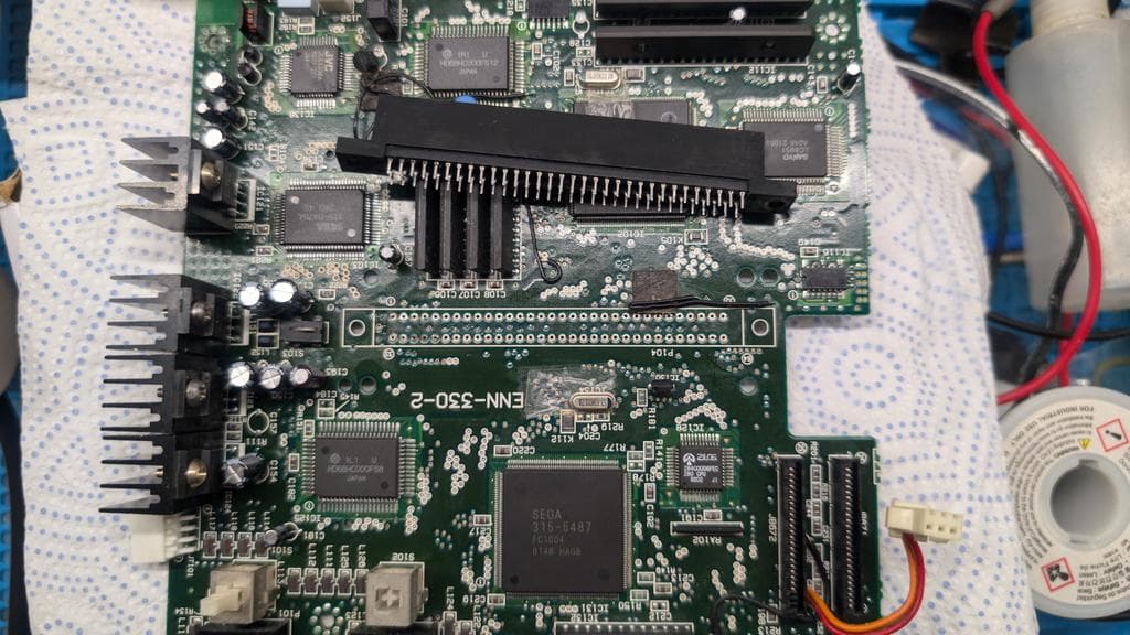 Sega Wondermega main board with cartridge connector removed, showing corroded cartridge detection button components and exposed PCB traces during repair work.