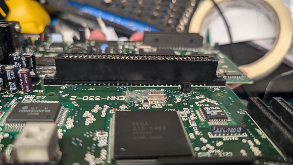 Close-up of Wondermega motherboard showing re-soldered connector and patched trace repair with kynar wire on green PCB.