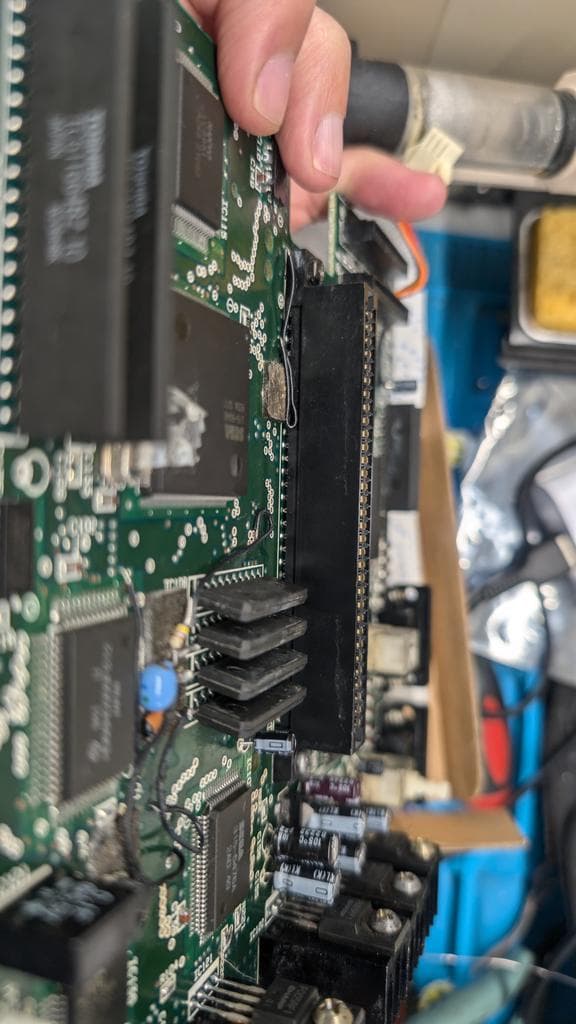 Close-up of repaired connector on Sega Wondermega PCB with fresh solder joints and kynar wire patch on broken trace.