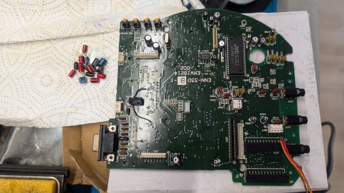 Wondermega circuit board with extracted capacitors showing corrosion and sludge damage during capacitor replacement surgery for CD freezing issue repair.