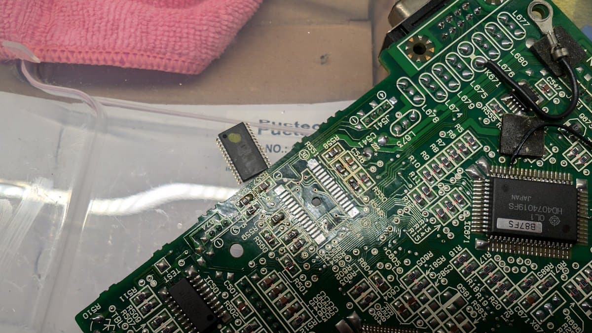 Close-up of green circuit board showing replaced BTL driver IC and surrounding solder joints during Wondermega repair work.