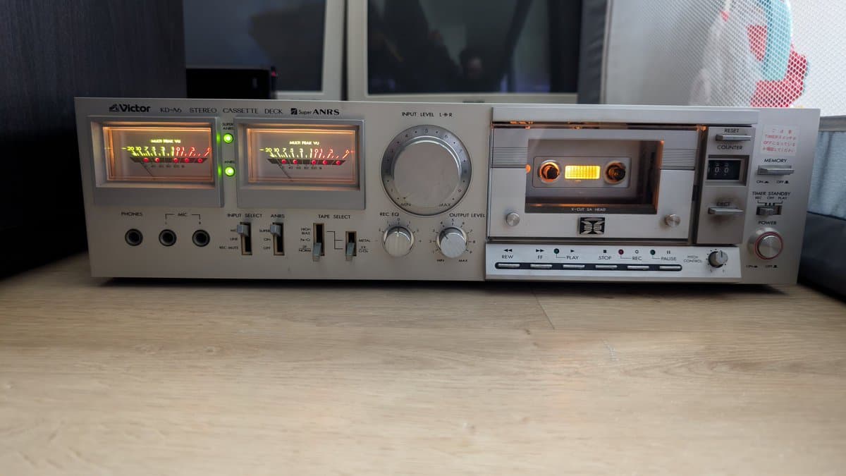 Victor KD-A6 stereo cassette deck powered on, showing illuminated VU meters with glowing tubes and internal capacitors visible inside the chassis.