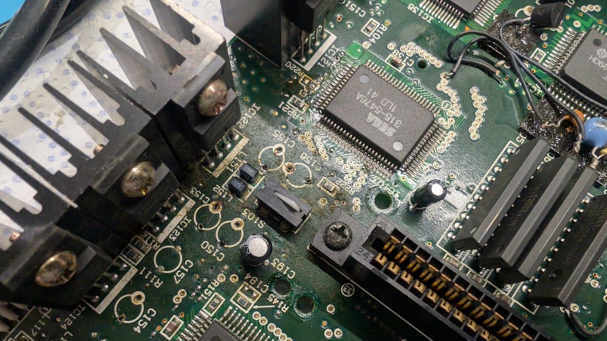 Victor RG-M1 motherboard during recap with visible capacitor leakage near voltage regulators and fresh solder joints from board restoration work.