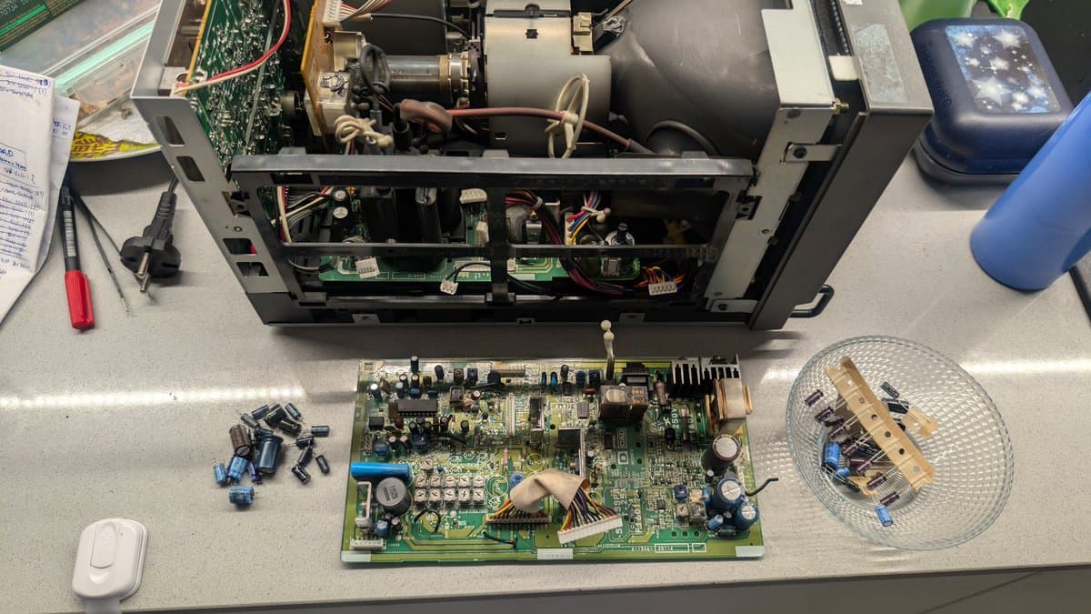 Sony PVM-9045QD PSU board laid out for recap; removed capacitors and cleaning supplies visible, white vinegar and isopropyl alcohol prep shown.