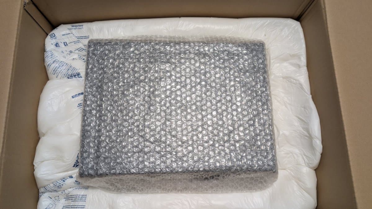 Sharp X68000 tower model in shipping box, wrapped in bubble wrap and white protective packaging material.