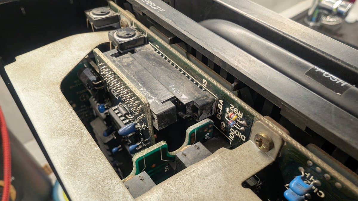 Interior of Sharp X68000 showing RAM expansion card loosened during shipping, circuit boards, capacitors, and connectors requiring reseating.