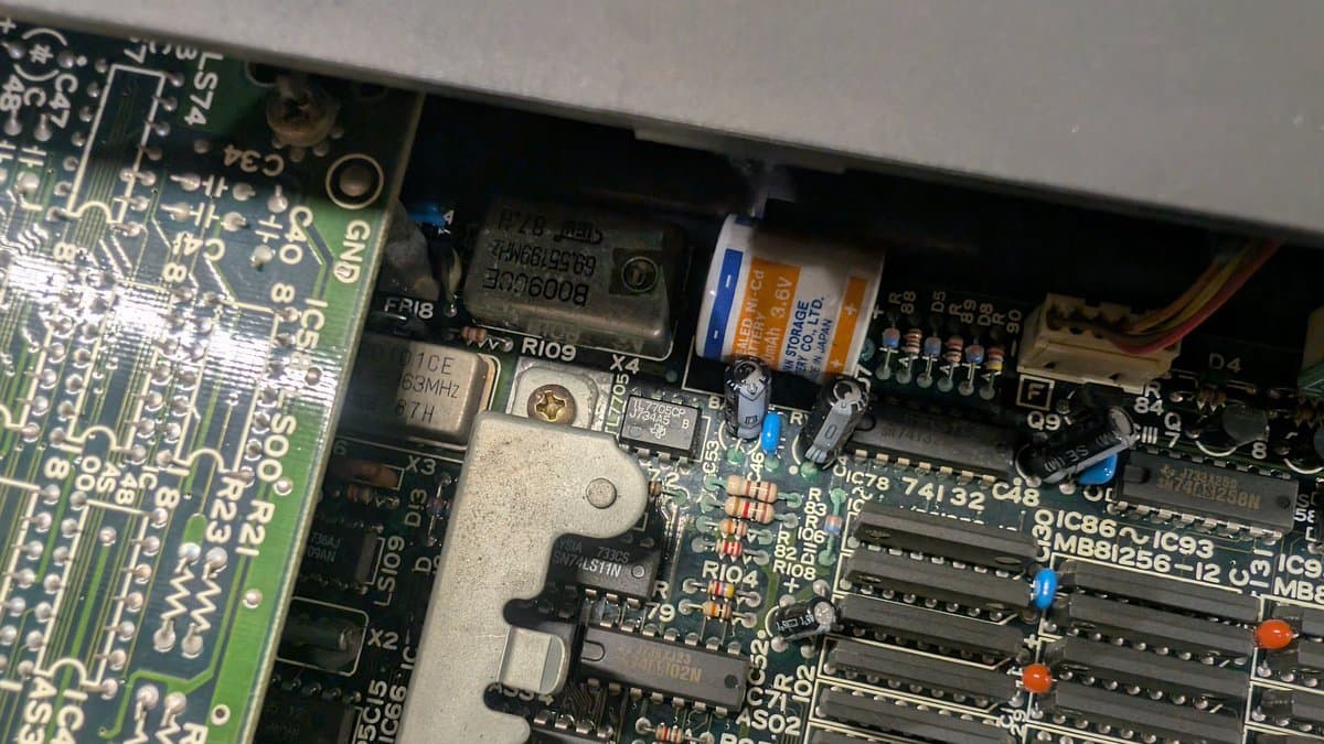 Battery leakage corrosion on X68000 motherboard cleaned with vinegar; visible capacitors, ICs, and corroded traces partially restored.