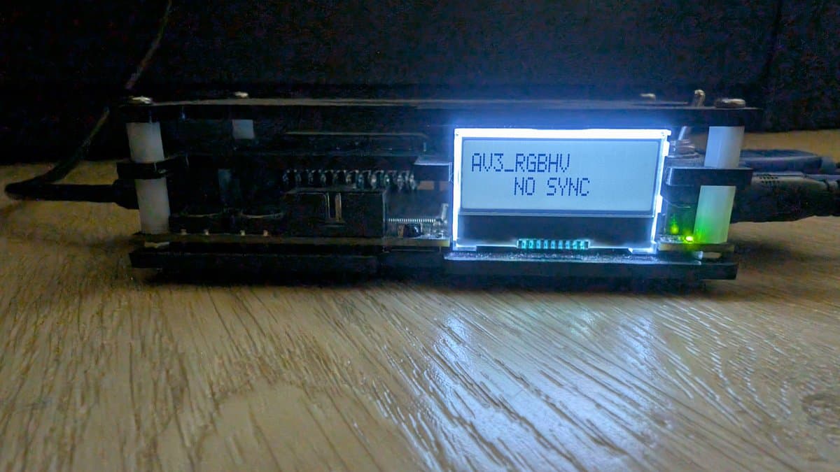 Sharp X68000 with VGA adapter and OSSC displaying "AUZ_RGBHU NO SYNC" on LCD screen; green LED lit, wooden workbench surface.
