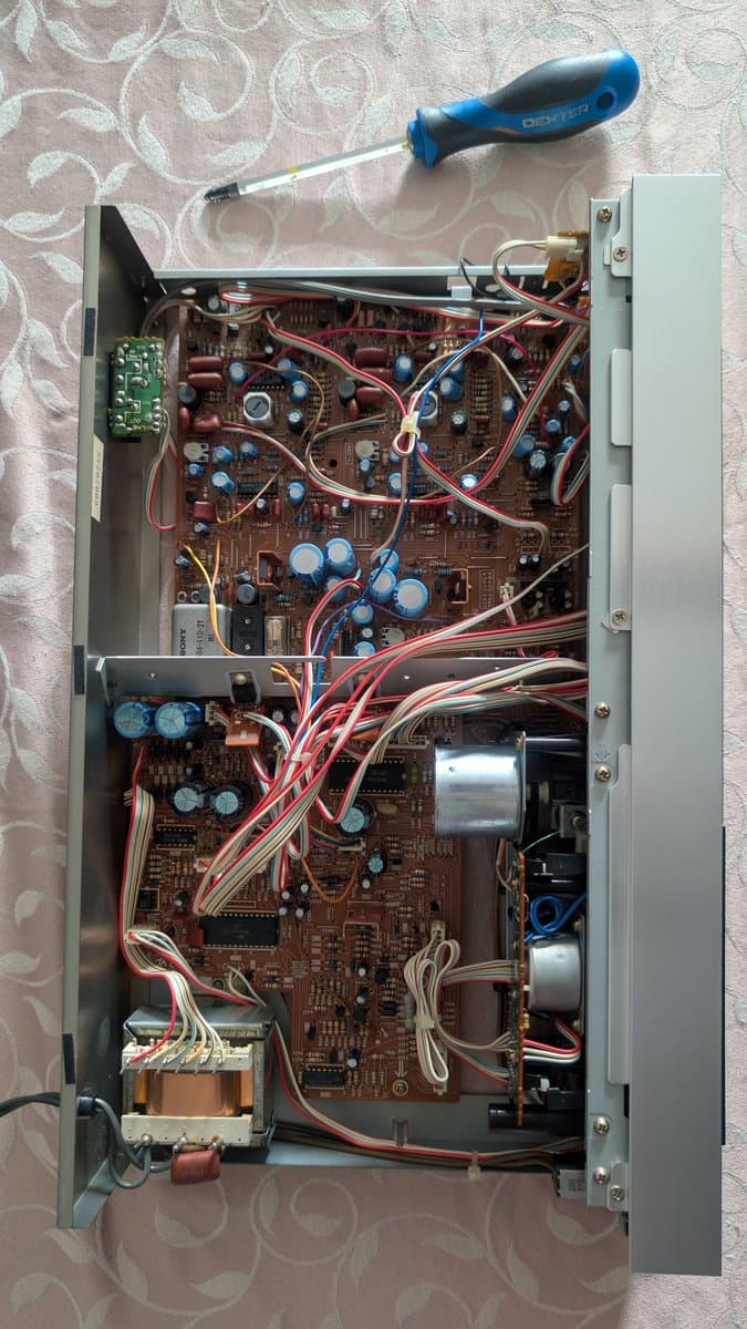 Interior of Sony TC-FX66 tape deck showing circuit boards, capacitors, transformers, and wiring with screwdriver positioned for repair work.