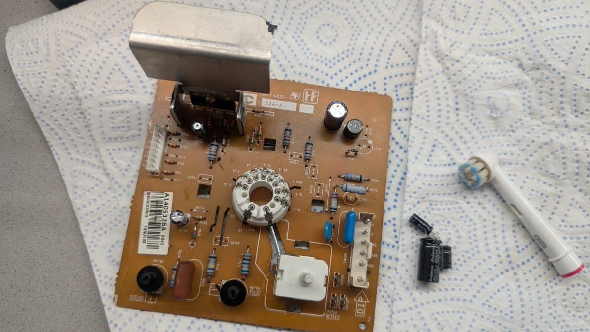 Sony PVM-14L1 neck board during recapping: PCB with electrolytic capacitors, resistors, and reflowed solder joints; metal heat sink and tools visible.