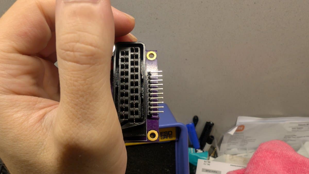 Hand holding SCART breakout board with desoldered pins and 1K resistor installation for PVM-14L1 RGB mod.