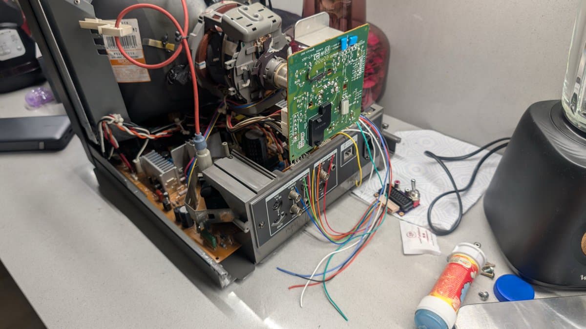 RGB mod PCB with multicolored wires connected to input board connector; heat-shrink tubing visible on solder joints during PVM-14L1 modification.