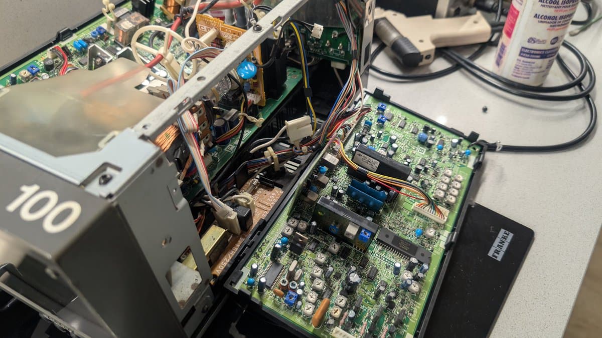 Sony PVM-6041Q internals during restoration: green PCBs, power supply components, wire harnesses, and cleaning supplies visible on workbench.
