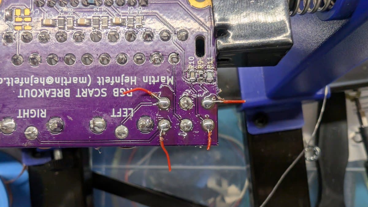 Purple RGB mod PCB with red wire soldered to pin, bent outer pins visible, solder joints connecting wires to middle pins.