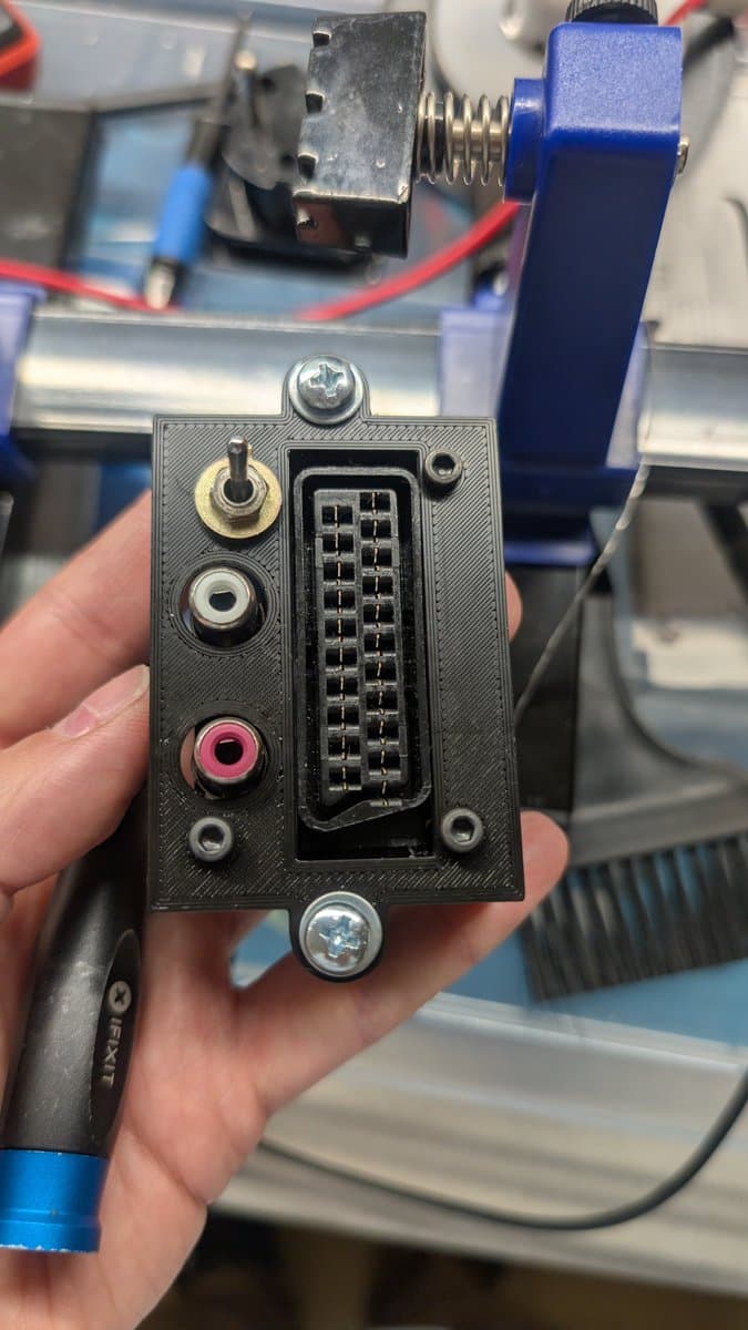 Custom RGB mod enclosure held in hand, showing toggle switch, audio jacks (RCA and mono), and internal PCB with terminal blocks for wiring connections.