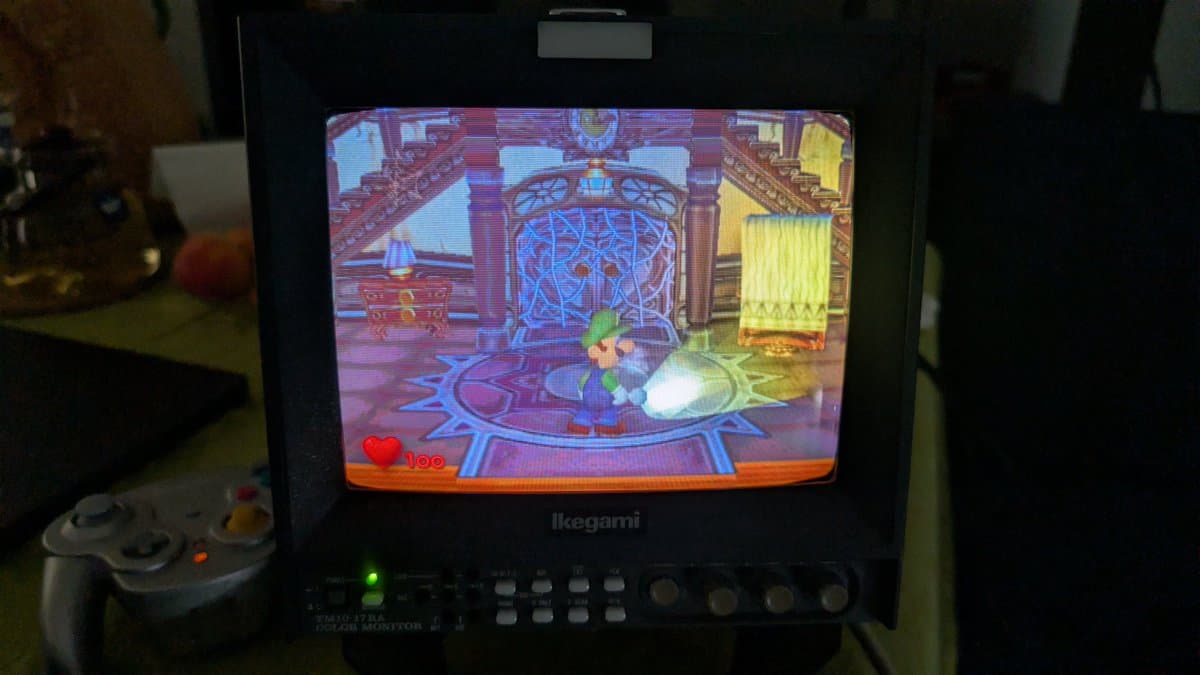 Restored Indigo GameCube displaying Luigi's Mansion on CRT monitor via Ikegami screen; console undergoing testing post-recapping.