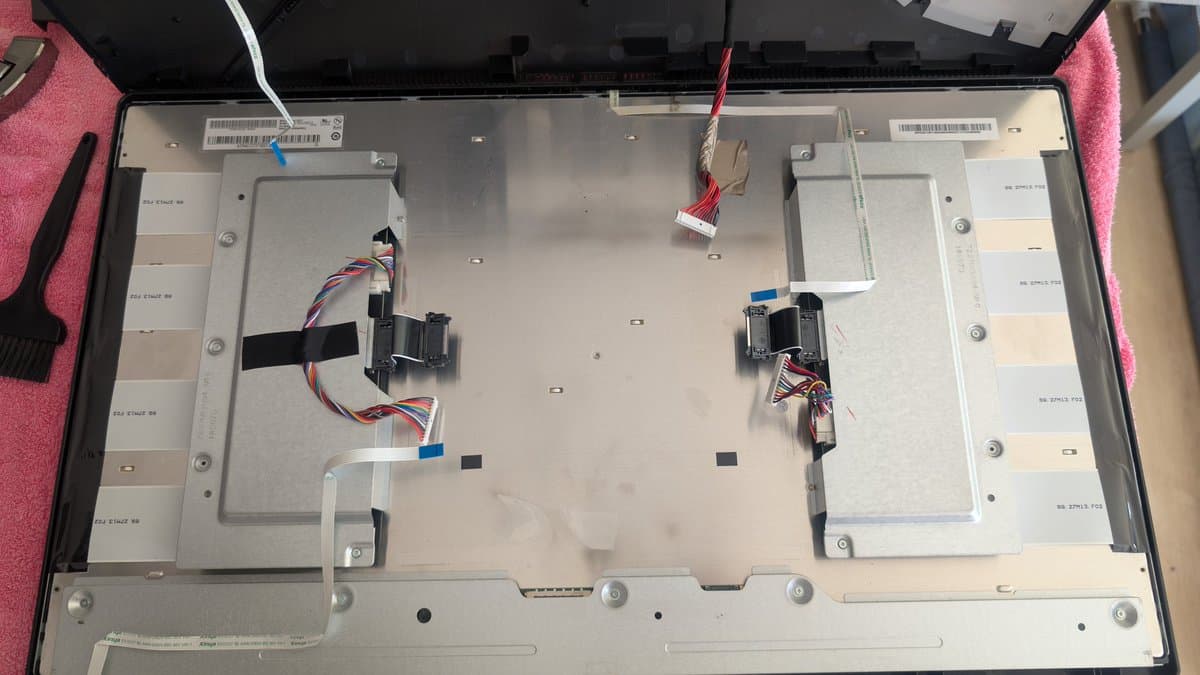 Asus PG27UQ monitor interior with removed panels exposing dual fans and multicolored wiring harnesses during maintenance refurbishment.