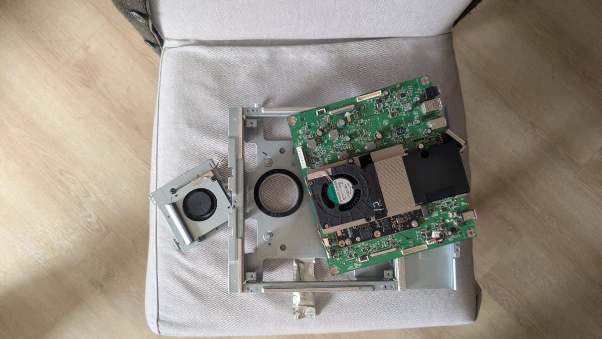 Disassembled Asus PG27UQ monitor internals showing dusty cooling fans, green PCB boards, and thermal paste residue on heatsink during refurbishment.