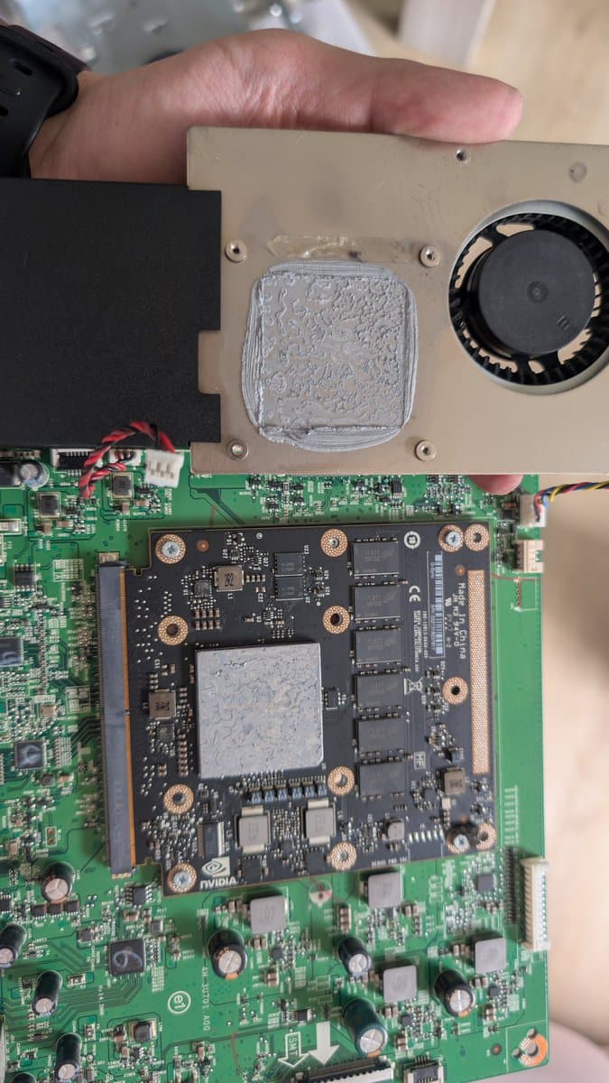 Disassembled Asus PG27UQ monitor showing mainboard and GPU module with crusty thermal paste and dust accumulation on heatsinks.