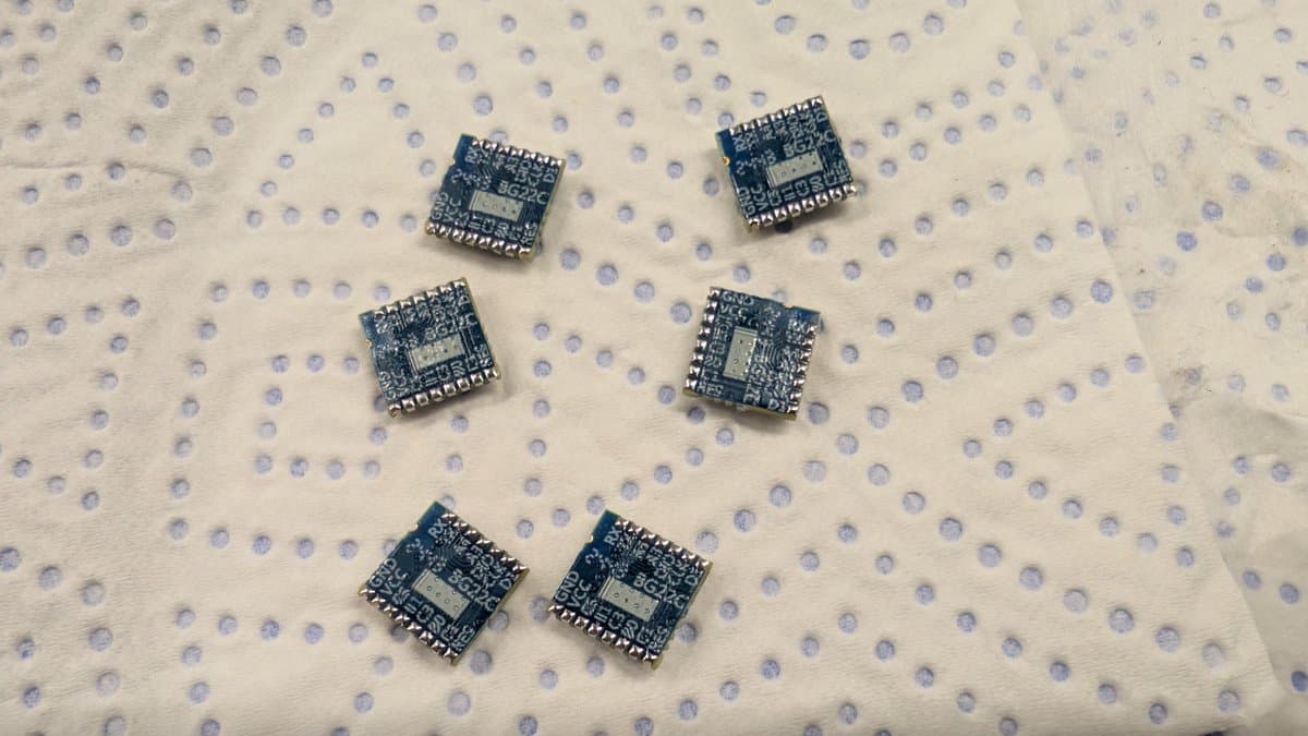 Six tinned EFR32 MCU chips arranged on dotted antistatic mat for WavePhoenix receiver assembly.