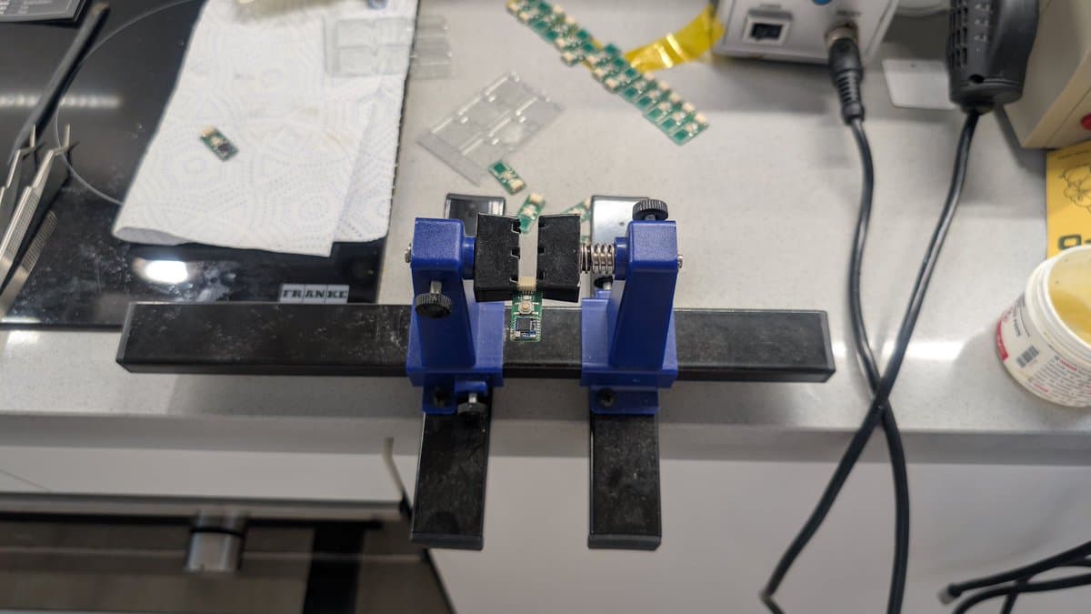WavePhoenix PCB with two blue vices holding black heatsinks, MCUs and components soldered in place on workbench.