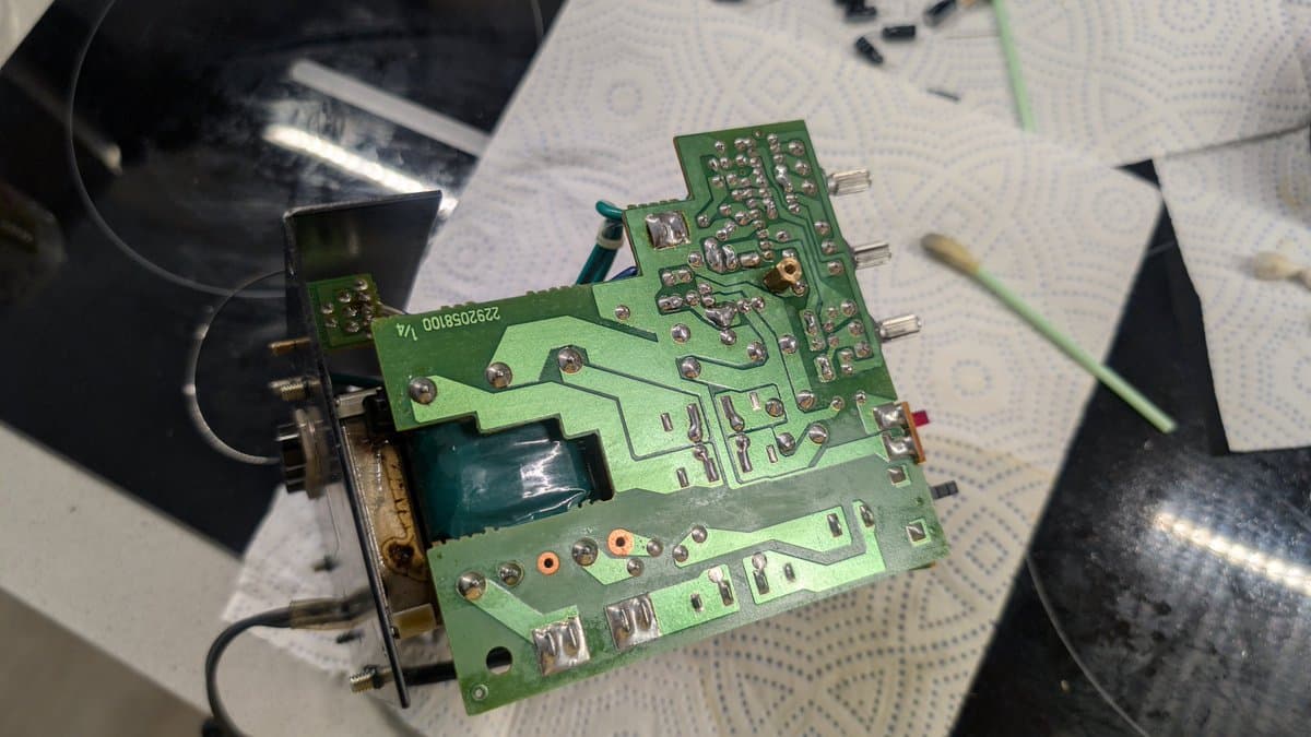Green PCB with reflowed solder joints, capacitor replacement, and schematic notes visible during BOSS MA-12AV speaker repair.