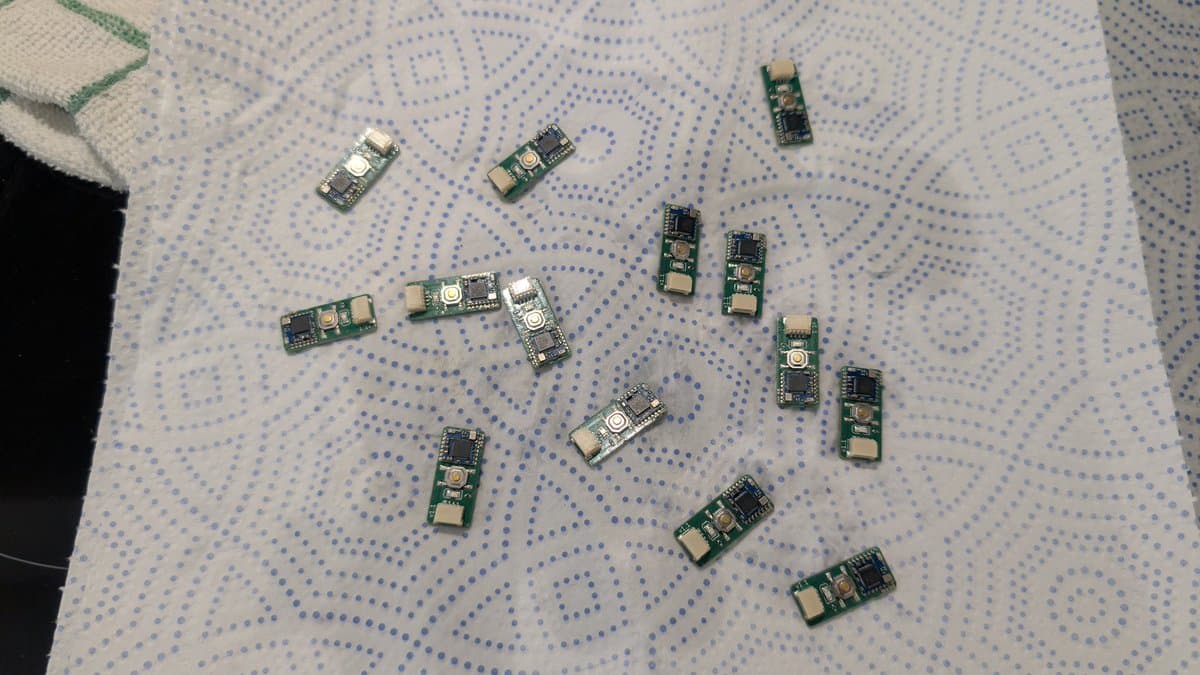 Multiple cleaned WavePhoenix receiver PCBs laid out on dotted paper before testing, showing green circuit boards with components and solder joints.