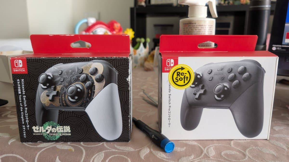 Two Nintendo Switch Pro controller boxes on table: left shows Zelda Tears of the Kingdom edition with ornate design, right shows standard black Re-Soft model with yellow sticker.