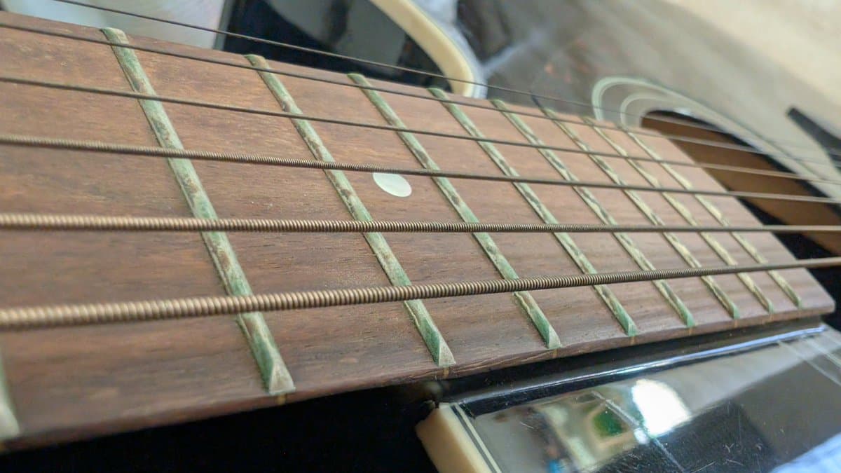 Yamaha FX370C fretboard close-up showing cleaned frets with inlays and newly installed strings after maintenance.