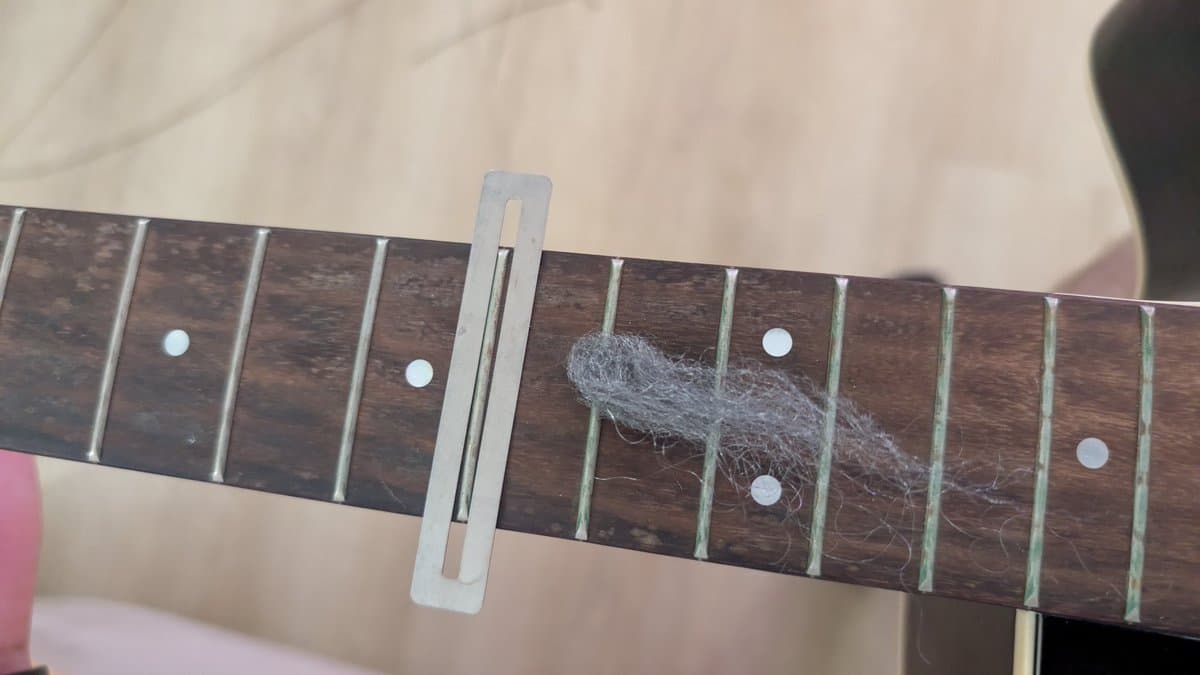 Yamaha FX370C fretboard with fret guard installed, steel wool visible on frets during oxidation removal, old strings removed.