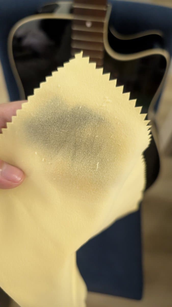 Hands applying lemon oil to Yamaha FX370C fretboard during cleaning and maintenance, showing treated rosewood surface.