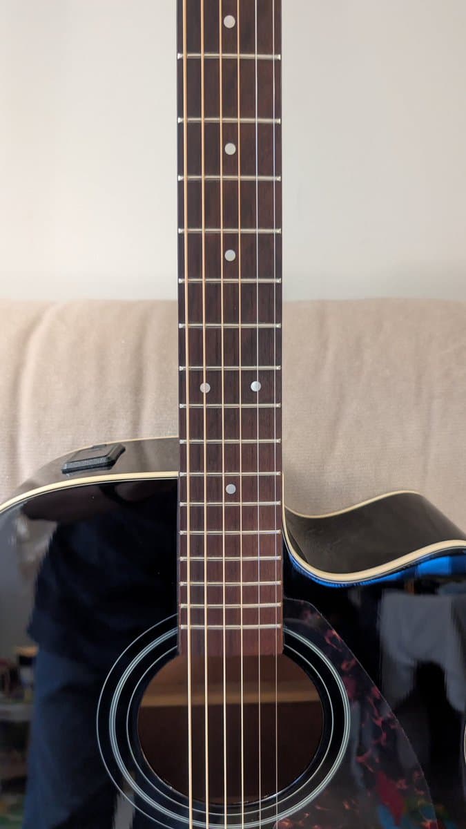 Yamaha FX370C 12-string acoustic guitar with cleaned fretboard, new strings, and polished black finish after maintenance.