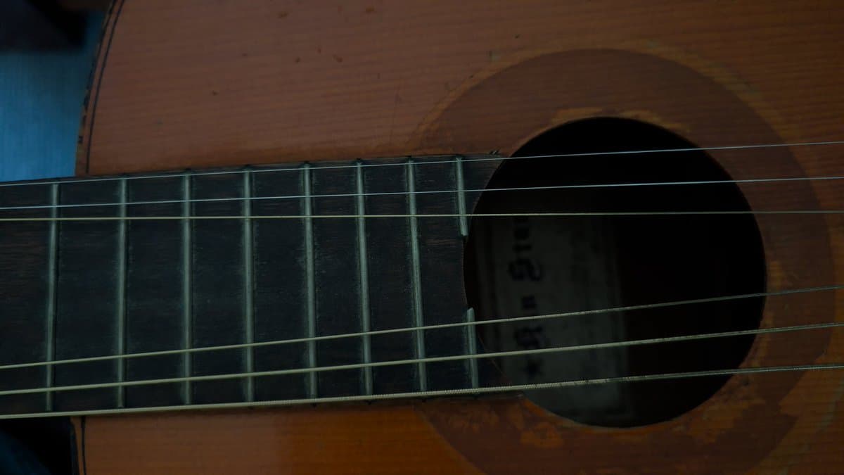 Close-up of acoustic guitar fretboard and strings showing cleaned frets and polished body after restoration work.