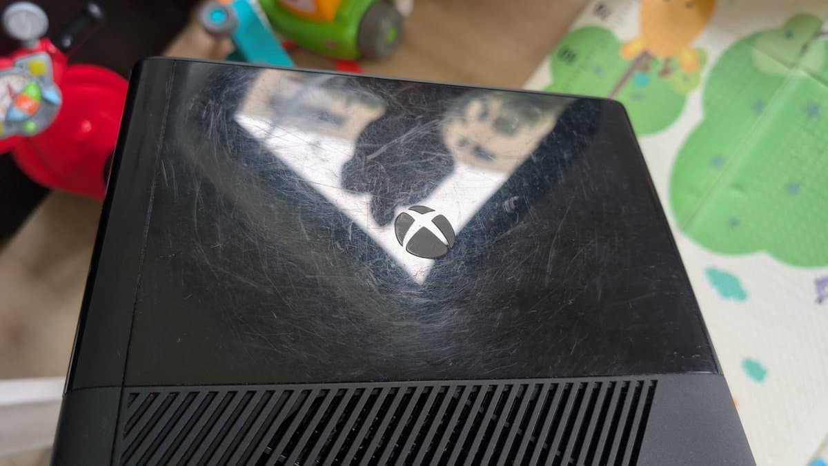 Xbox 360 E shell top with visible scratches and wear marks, showing cosmetic damage being addressed during restoration.