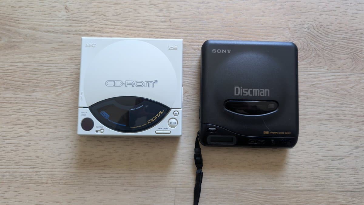 NEC PC Engine CD-ROM2 next to Sony Discman on wooden surface; donor unit for laser replacement during restoration.