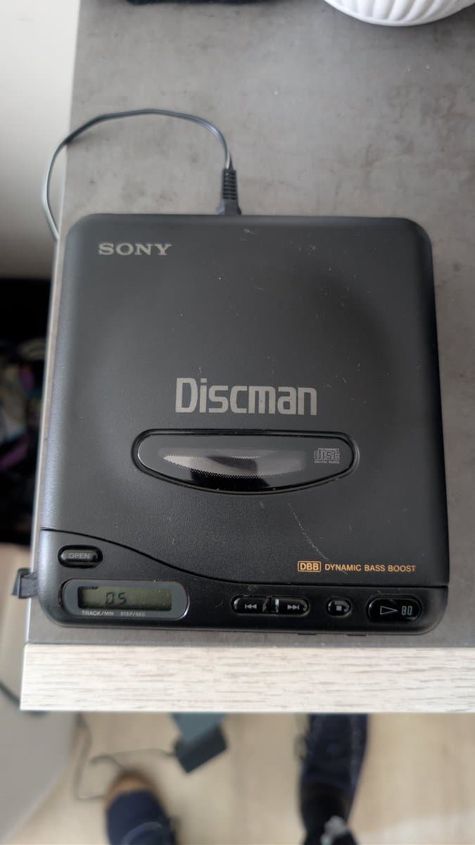 Sony Discman portable CD player positioned next to NEC PC Engine CD-ROM2 during laser transplant repair procedure.