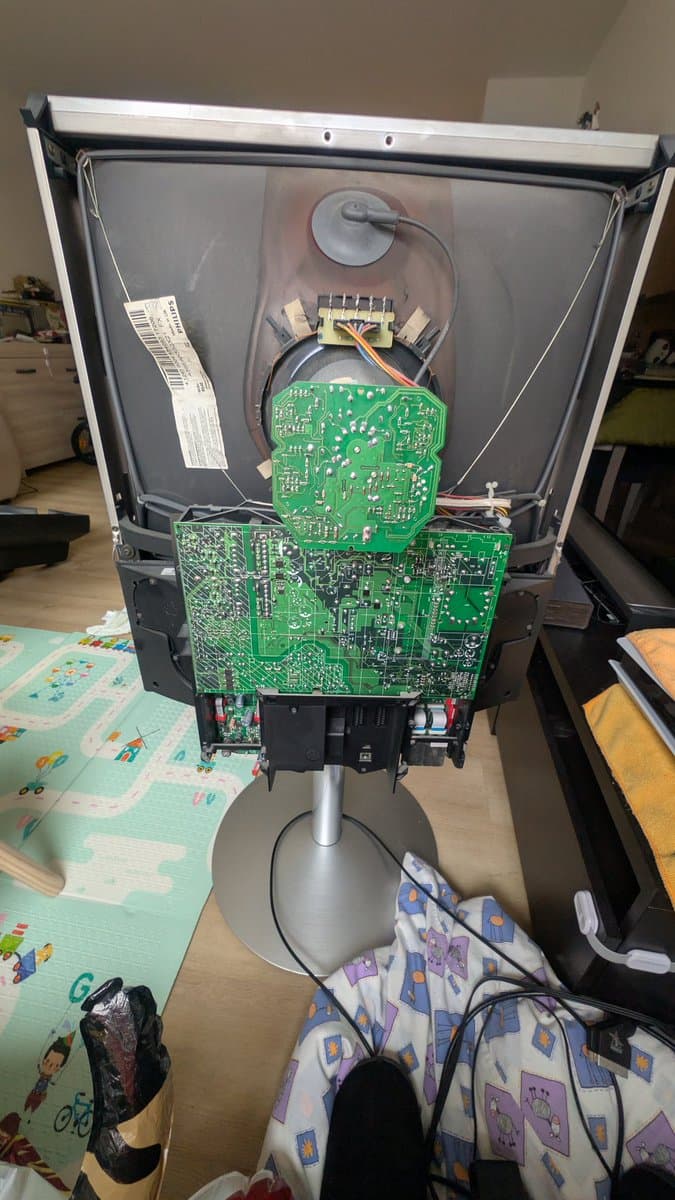 B&O Beovision 1 internals with back cover removed, showing green PCBs, transformer, and internal wiring during magic smoke repair investigation.
