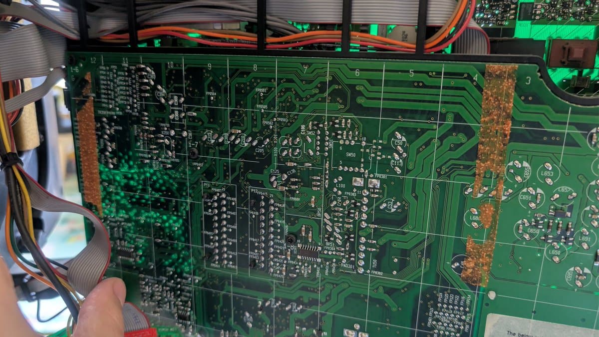Burnt X2 safety capacitor on B&O Beovision 1 mainboard, showing catastrophic thermal damage and charring among surrounding components.
