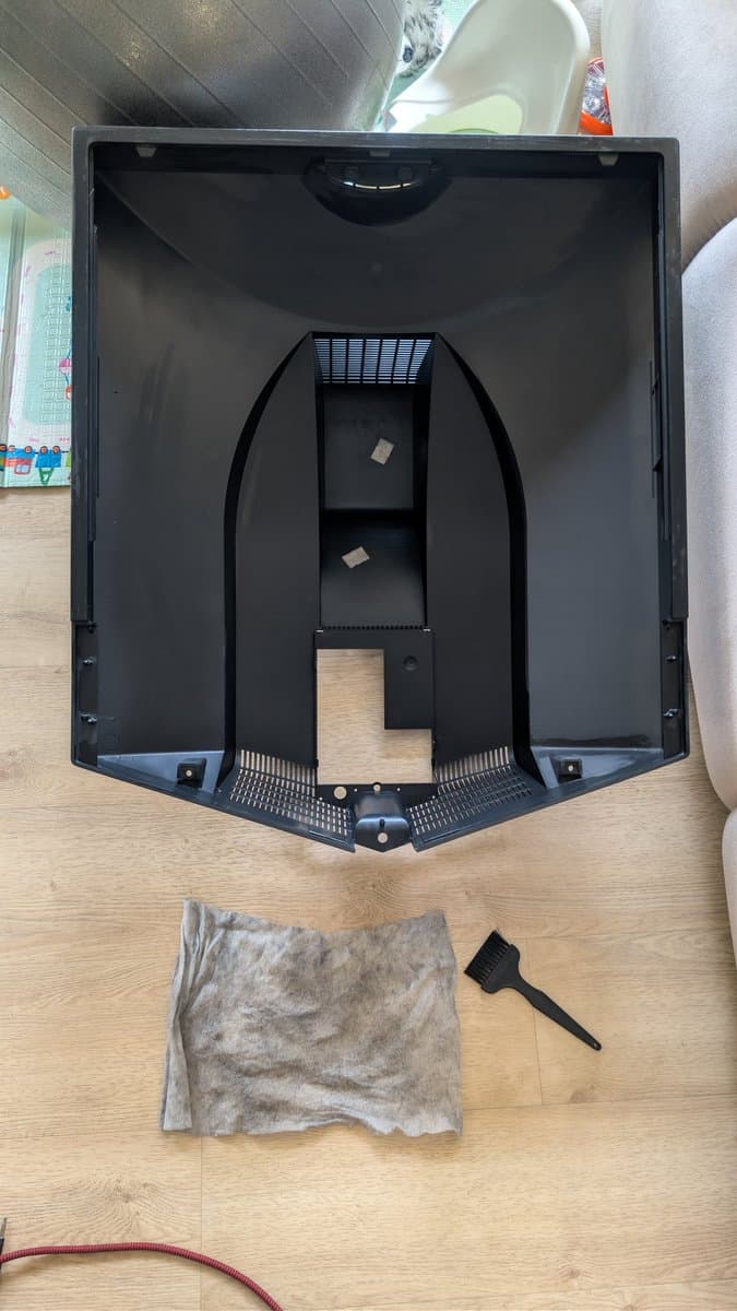Disassembled B&O Beovision 1 CRT chassis interior showing damaged X2 safety capacitor, internal components, cleaning brush, and debris cloth on wooden workbench.