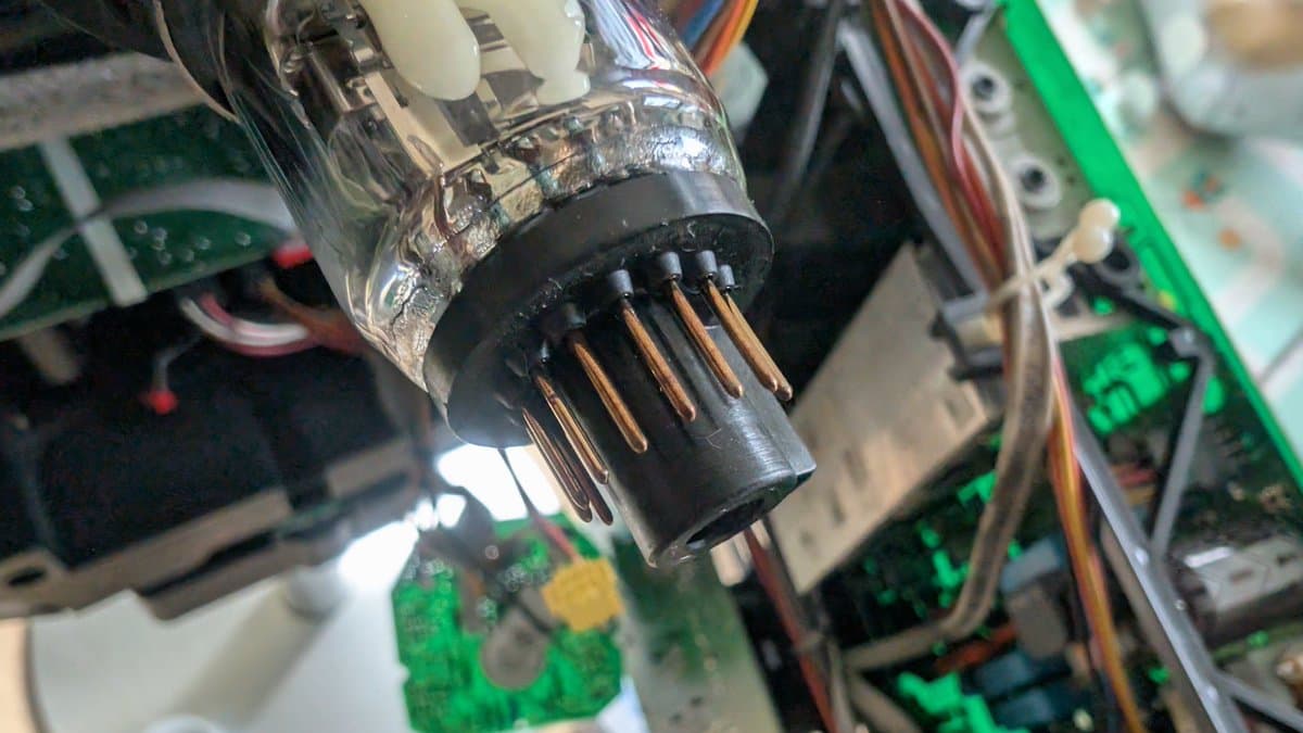 Corroded X2 safety cap with burned copper pins being cleaned, showing oxidation damage from smoke event on B&O Beovision 1 CRT.